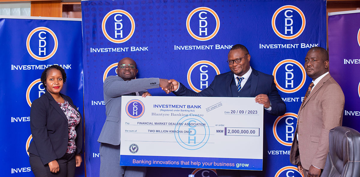 Mr Zondwayo Mafuleka, (2nd left), CDH Investment Bank, Chief Treasury Officer, hands over funds to Mr Yamikani Bobe Financial Market Dealers Association (FIMDA) Publicity Secretary (3rd left)