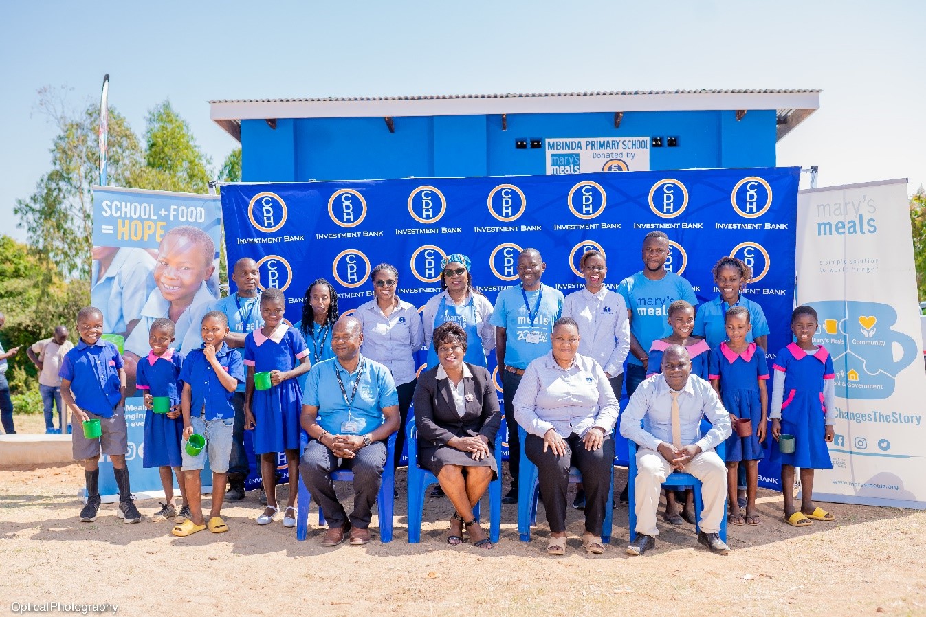 The head teacher and some learners from Mbinda Junior Primary School, some Mary’s Meals Malawi and CDH Investment Bank representatives pose with the Guest of Honor, Zelita Zamula, Ministry of Education Principal Education Officer in front of the new school kitchen and feeding block. The head teacher and some learners from Mbinda Junior Primary School, some Mary’s Meals Malawi and CDH Investment Bank representatives pose with the Guest of Honor, Zelita Zamula, Ministry of Education Principal Education Officer in front of the new school kitchen and feeding block.