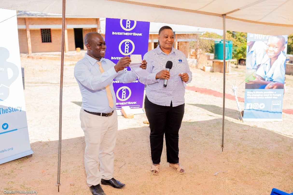 Mr Joe Magodi, head teacher of Mbinda Junir Primary School receives a gift from CDH Investment Bank Chief Human Capital Development Officer, Mrs Ivy Kwatiwani Mr Joe Magodi, head teacher of Mbinda Junir Primary School receives a gift from CDH Investment Bank Chief Human Capital Development Officer, Mrs Ivy Kwatiwani