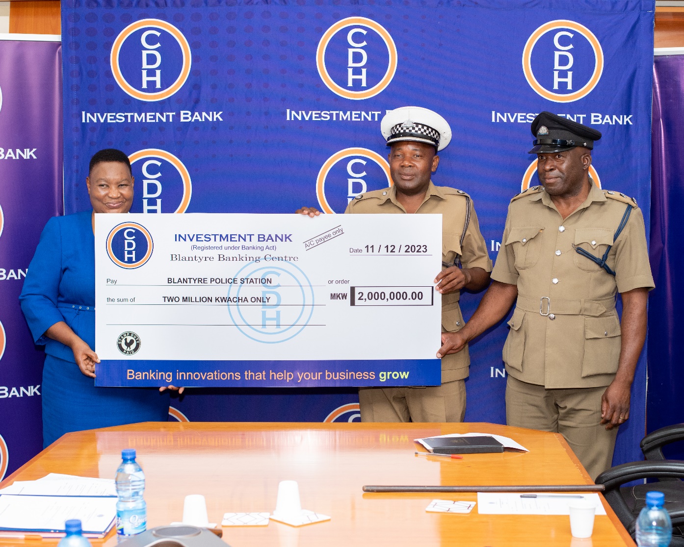 Ms Ivy Kwatiwani, CDHIB Chief Human Capital and Development Officer hands over funds to Superintendent Jackson Silungwe (Centre)