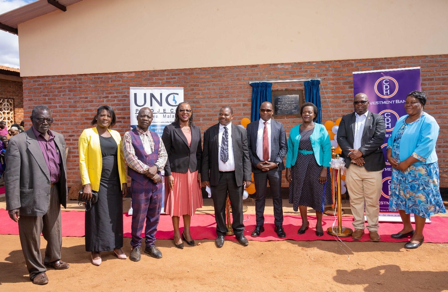 Representatives from Dzama community, UNC Project Malawi, CDH Investment Bank pose with the Guest of Honor Mrs Judith Chiwoko (3rd right) after unveiling the school block building plaque. Representatives from Dzama community, UNC Project Malawi, CDH Investment Bank pose with the Guest of Honor Mrs Judith Chiwoko (3rd right) after unveiling the school block building plaque.